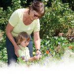 Frau und Kind betrachten Blüte einer Blume