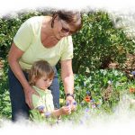 Frau und Kind betrachten Blüte einer Blume