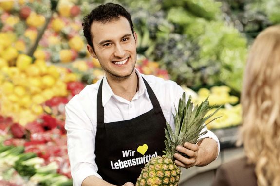 Hakan, Azubi im EDEKA-Markt, präsentiert eine Ananas