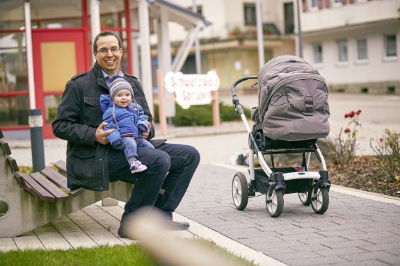Vater sitzt auf der Bank mit seinem Kind auf dem Schoß