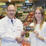 Manomama-Wettbewerb-Gewinnerin Luisa Dick erhält von Kaufmann Ingo Müller ihren Einkaufsgutschein